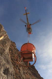 Photo d'un hélicoptère entrain de déplacer une bétonnière